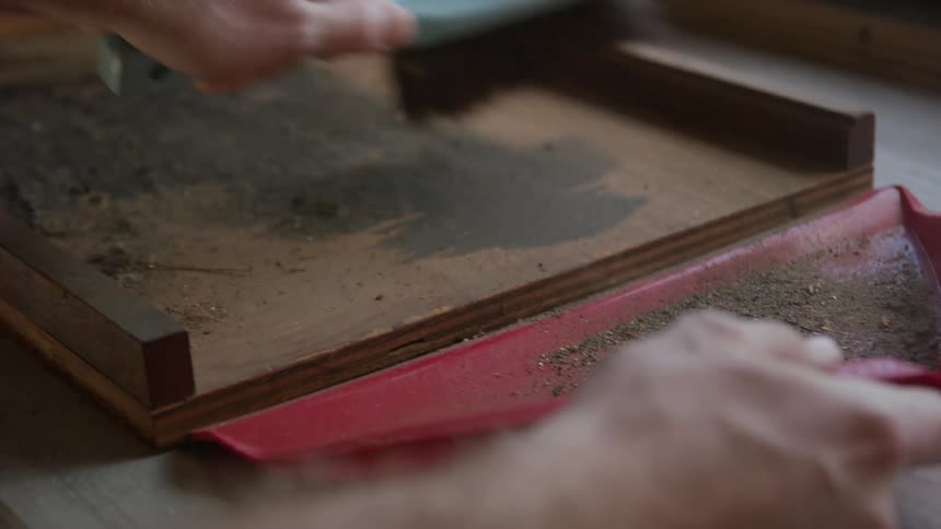 A man cleaning up dirt with a hand brush and dustpan