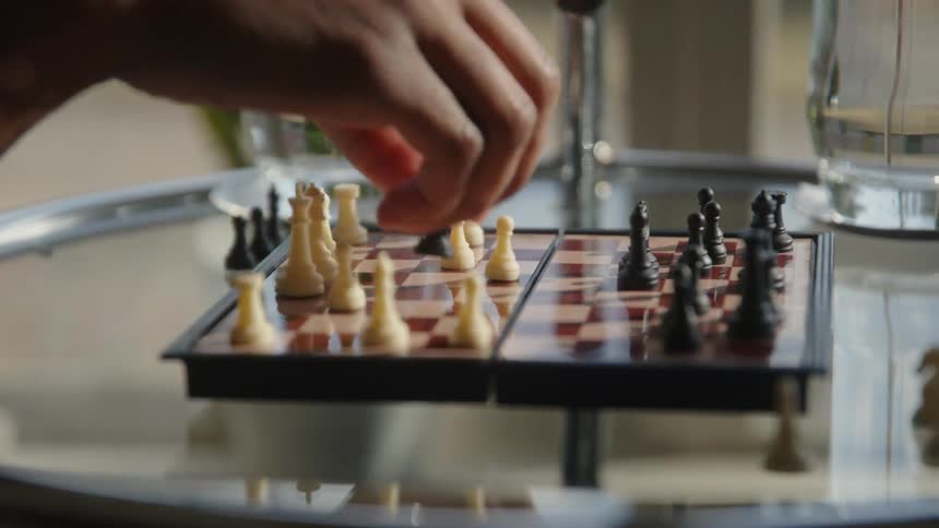 A person playing chess moves a piece and takes the opponents knight with a pawn