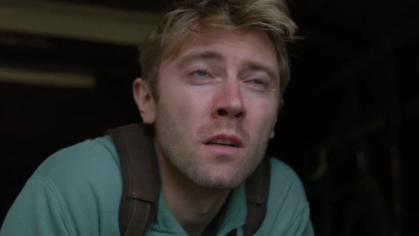 A man sneezes and closes his eyes as wind blows through his hair