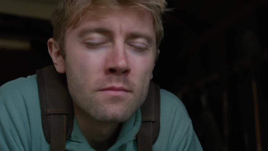 A man closing his eyes and taking a deep breath while a breeze blows on his face
