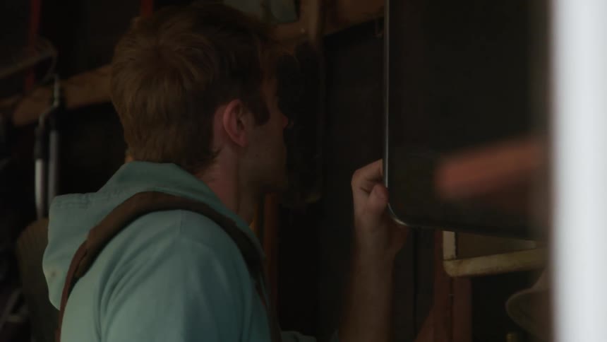 A man opens a mirrored medicine cabinet in a tool shed