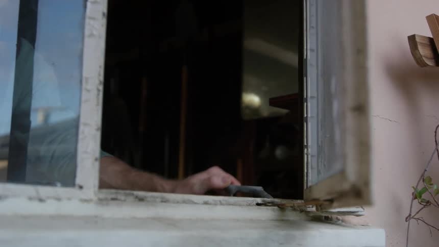 A man opening a house window and waving