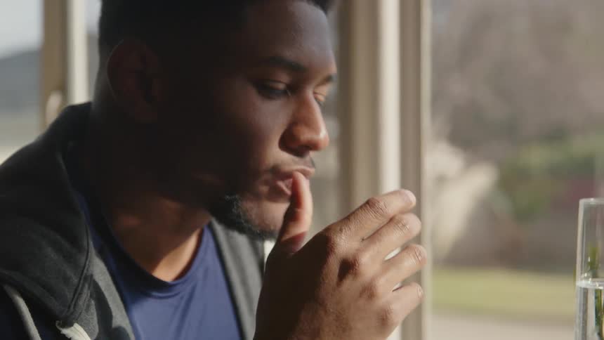 A man is sitting near a window and is thinking