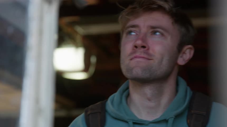 A close up of a mans face looking out a window and smiling
