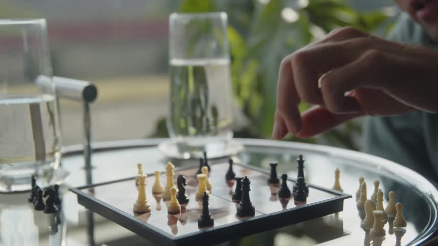 A man talks while he plays chess with a friend