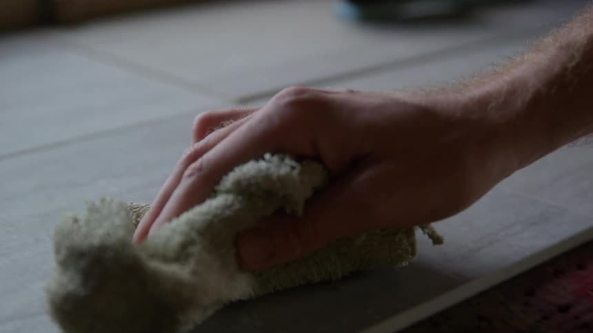 A man using a rag to wipe down a wooden counter
