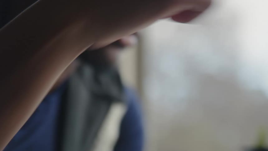 Close up of the face of a young man playing chess near a window