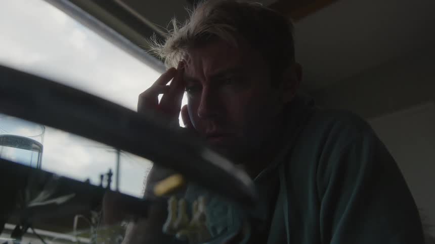 Close up of the face of a young man playing chess near a window