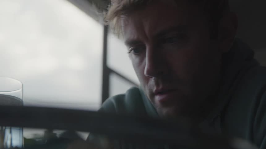 Close up of the face of a young man playing chess near a window