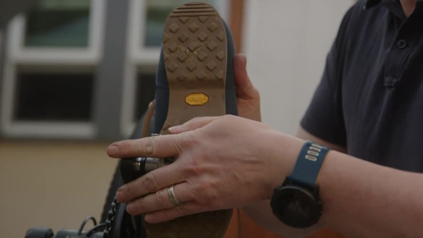 Close up of a man attaching a shoe to the pedal of a bicyclce outdoors