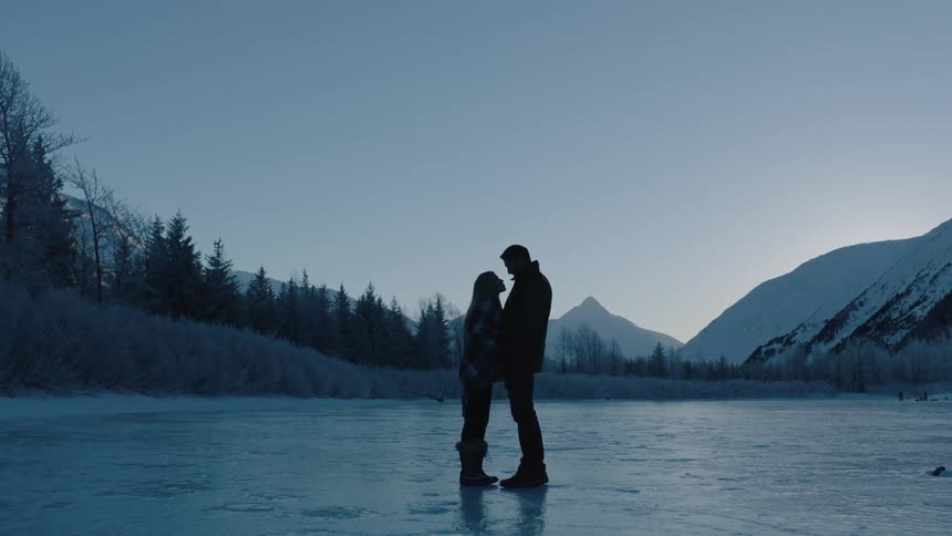 A man and woman are standing close together on ice