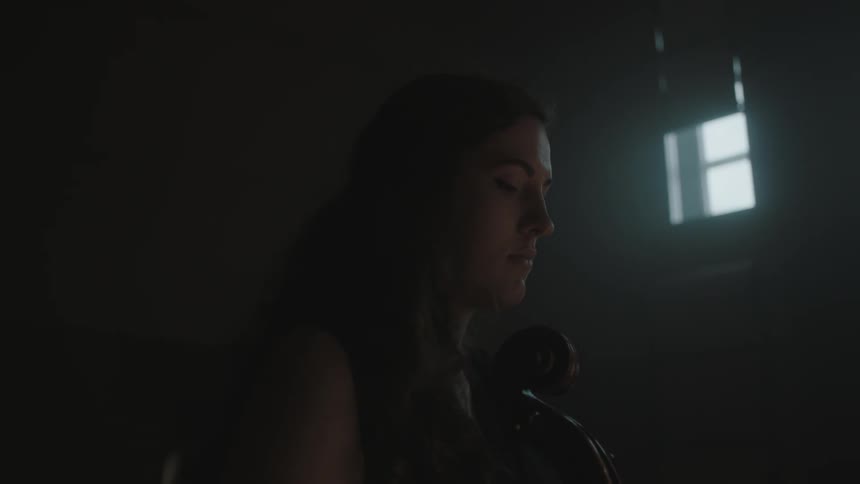 A woman is in a dark room looking down