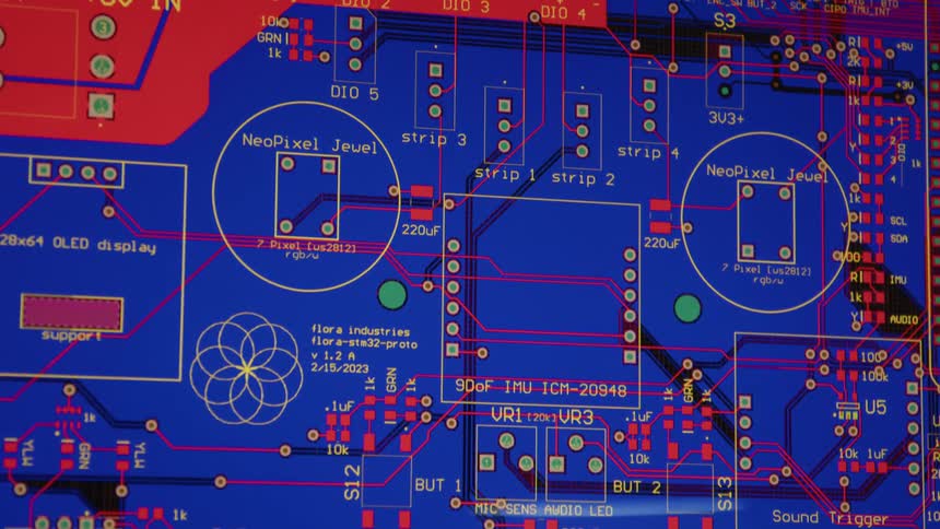 A blue and orange printed circuit board is covered in numerous contact points and components