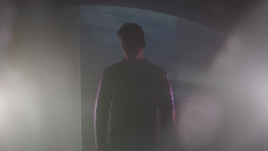 A man stands in a dark area with two lights