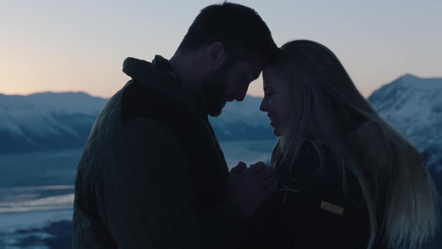 A man and woman put their heads together at sunset