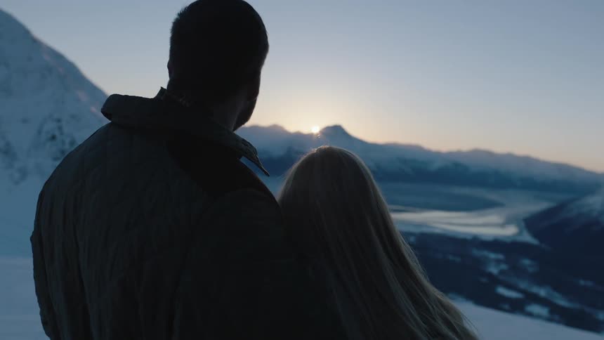 A man and woman looking into each others eyes and then turning to face a view