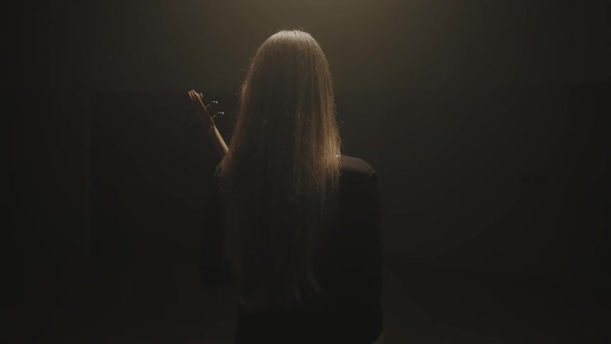 A woman is standing in the dark with an instrument