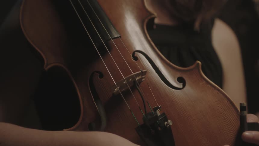 A woman holds a violin to her chest