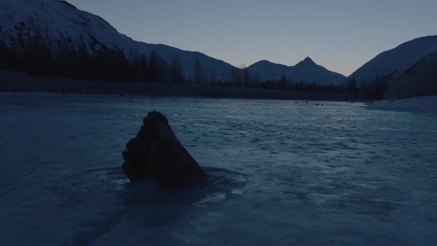 A rock jutting up out of a frozen lake