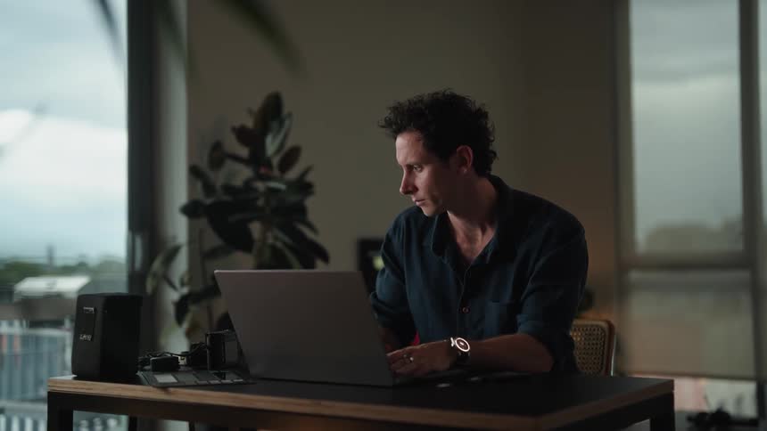 A man is typing on his laptop in his home