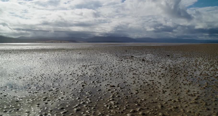 Water with dirt and bubbles in it and mountains in the far distance