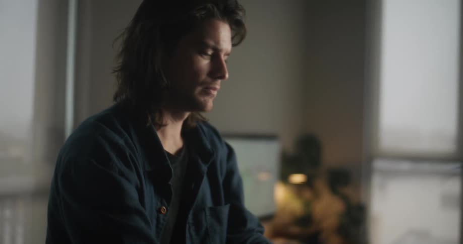 A man is working on his laptop and sitting indoors