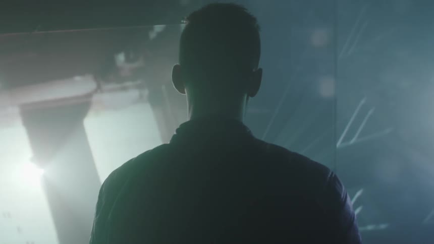 A man is walking toward a display of projected lights and images