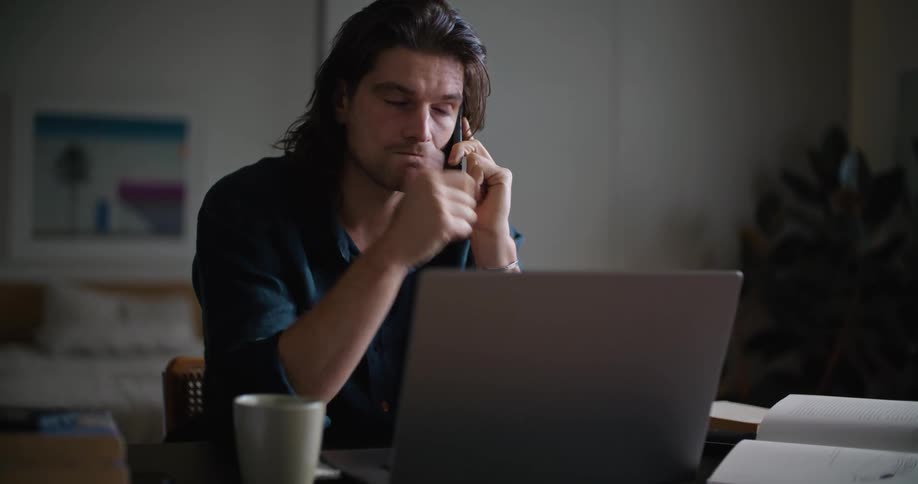 A man talks on the phone at his desk