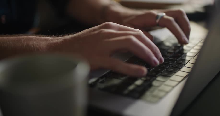 A man typing on a keyboard laptop