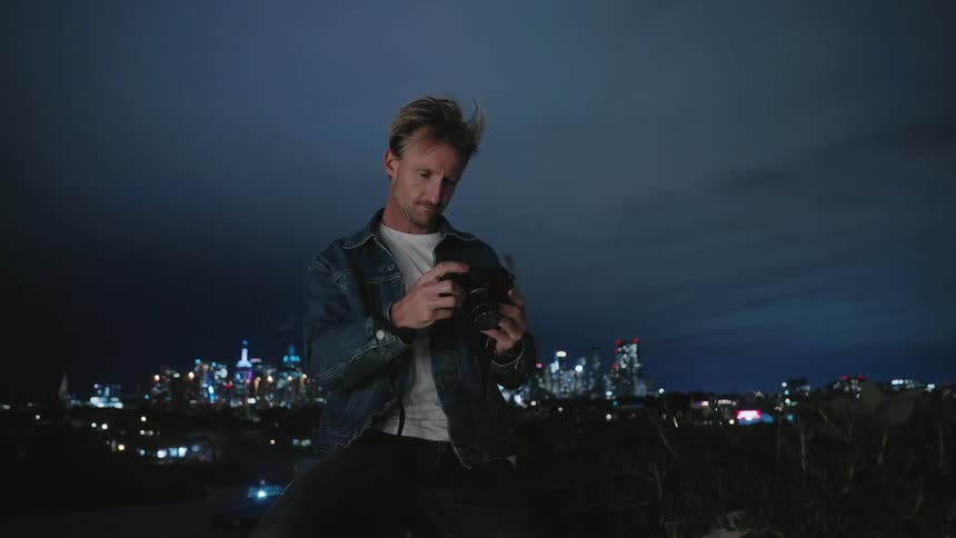 Man taking photographs an nighttime at a lookout point above the city