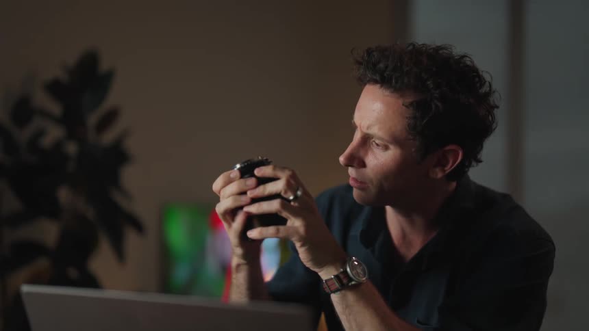 A man is sitting at his desk with a camera lens