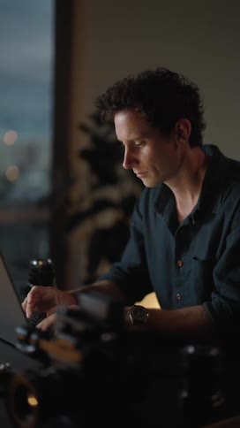 A man sitting in front of a laptop typing and looking contemplatively