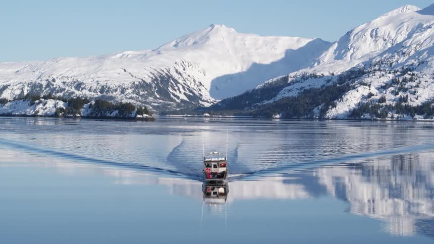 A boat sails in the water by a mountain