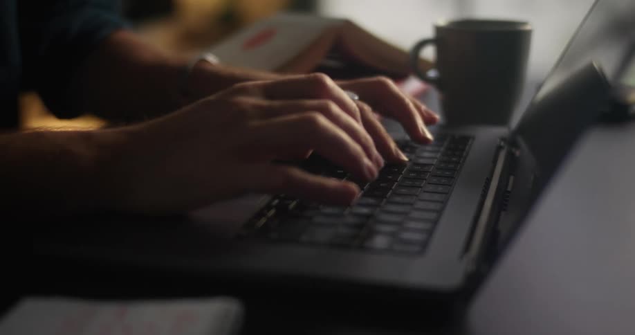 A person is typing on a laptop while sitting at a desk