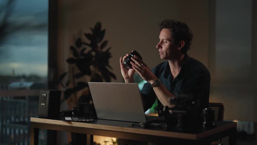 A man is looking at a camera as he talks on the laptop