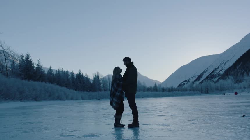 A man and a woman standing close together on an ice covered lake