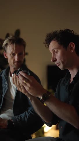 Two men look at and talk about a camera