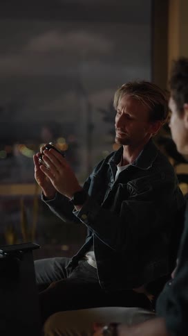 Two men examine a camera lens together