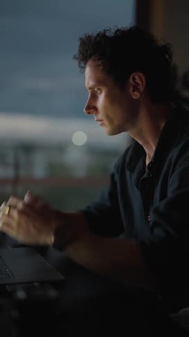 A man sitting and typing on his laptop and putting his hands on his chin