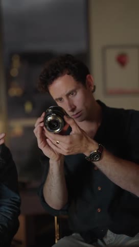 Two friends are looking at a camera lens together