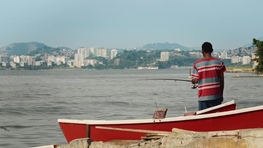 A man is fishing near the boats