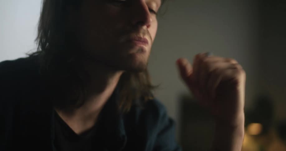 A man sitting with his hands on his head looking contemplatively