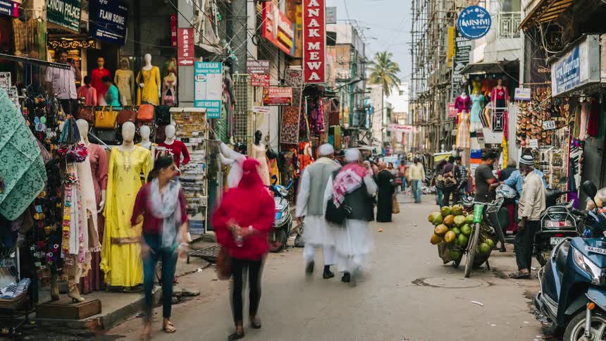 A crowd passes through a business district in a developing city