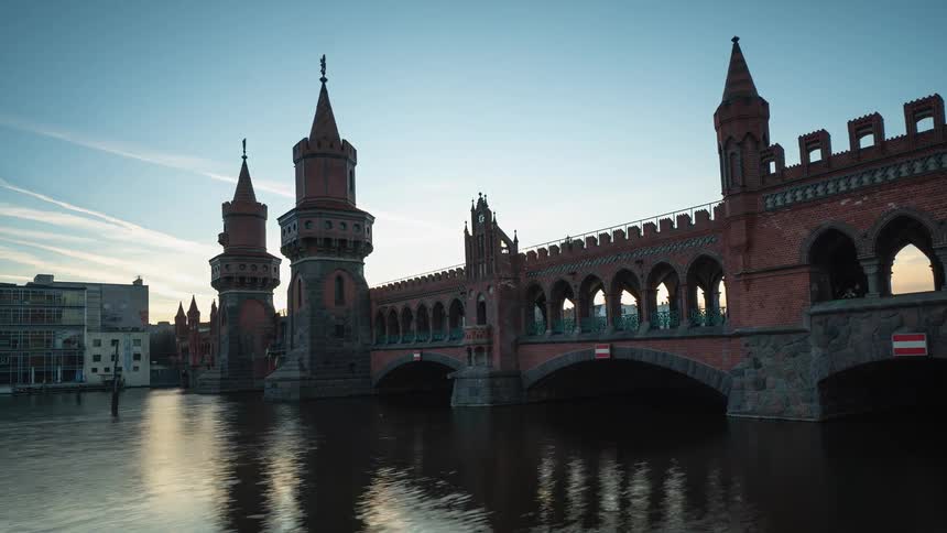 An architectural bridge over a waterway with traffic driving over the bridge and a boat traveling under it