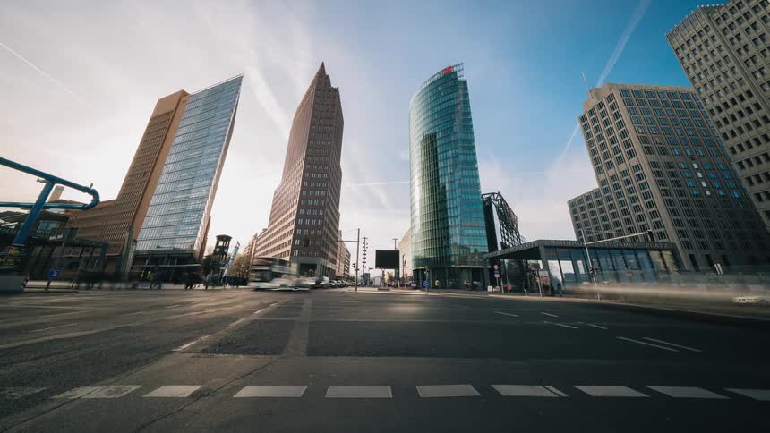 People and vehicles pass through a dense city intersection throughout the day