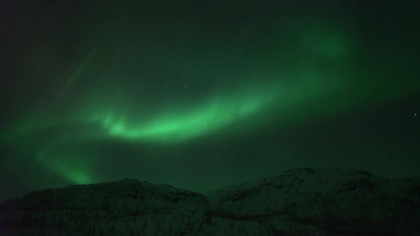 The night sky turns green over a mountain range