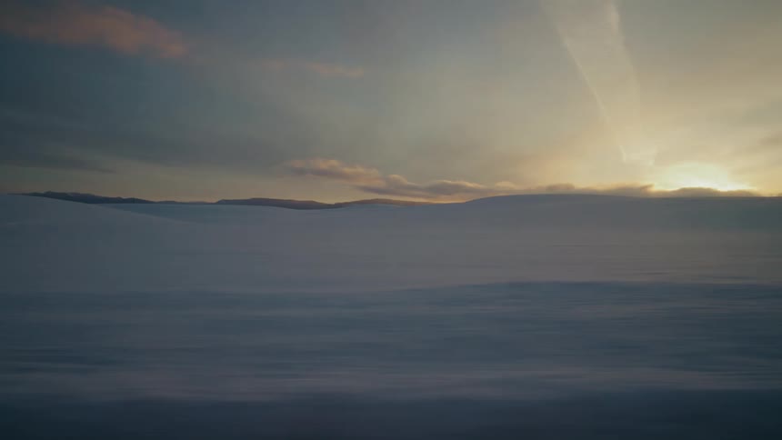The sun is setting in the horizon of a winter landscape