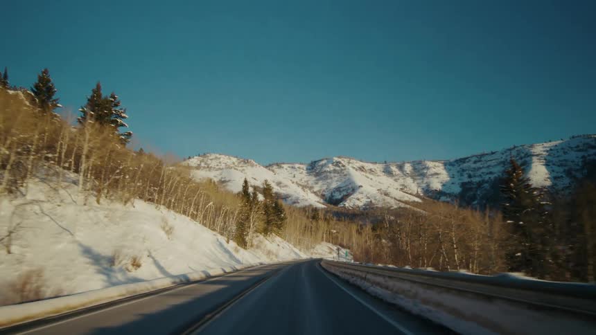 A narrow highway runs along snow covered mountains