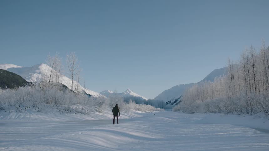 A man is walking along a snow covered field