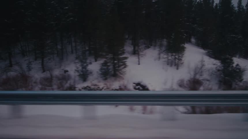 Driving through the snow covered forests in the mountains at sunset
